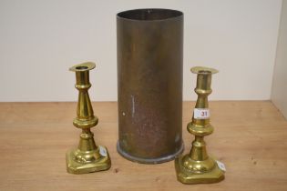 A pair of 19th Century brass candlesticks, measuring 20cm tall, and a brass artillery shell case