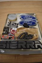 A collection of vintage plastic car badges, including Ford and Ghia