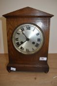 An Edwardian oak cased mantel clock having silvered roman numeral dial