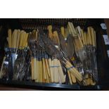 A basket of ivorine handled cutlery, including fish knives, forks, and spoons