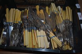 A basket of ivorine handled cutlery, including fish knives, forks, and spoons