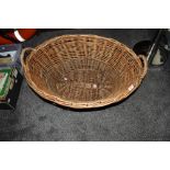 An oval wicker log basket, measuring 34cm tall, 72cm long, and 53cm wide