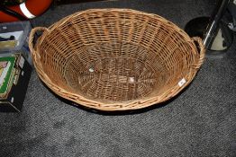 An oval wicker log basket, measuring 34cm tall, 72cm long, and 53cm wide