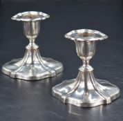 A pair of Edwardian silver candlesticks, of Chippendale influenced design with swept shaped oval