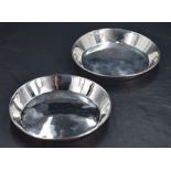 A pair of George V silver dishes or coasters, of circular form with angled booge and rolled rim,