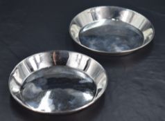 A pair of George V silver dishes or coasters, of circular form with angled booge and rolled rim,
