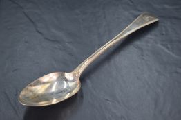 A George IV silver Old English Thread pattern serving spoon, engraved with crest 'A Dexter arm