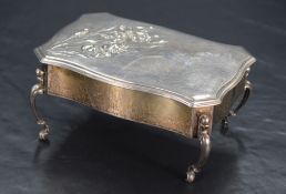 An Edwardian silver jewellery box, in the form of a commode table with serpentine outline and canted