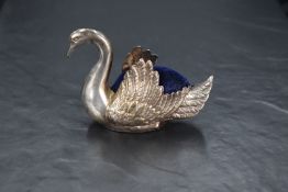 A 20th century white metal swan-from pin cushion, having embossed detail and blue velvet cushion,