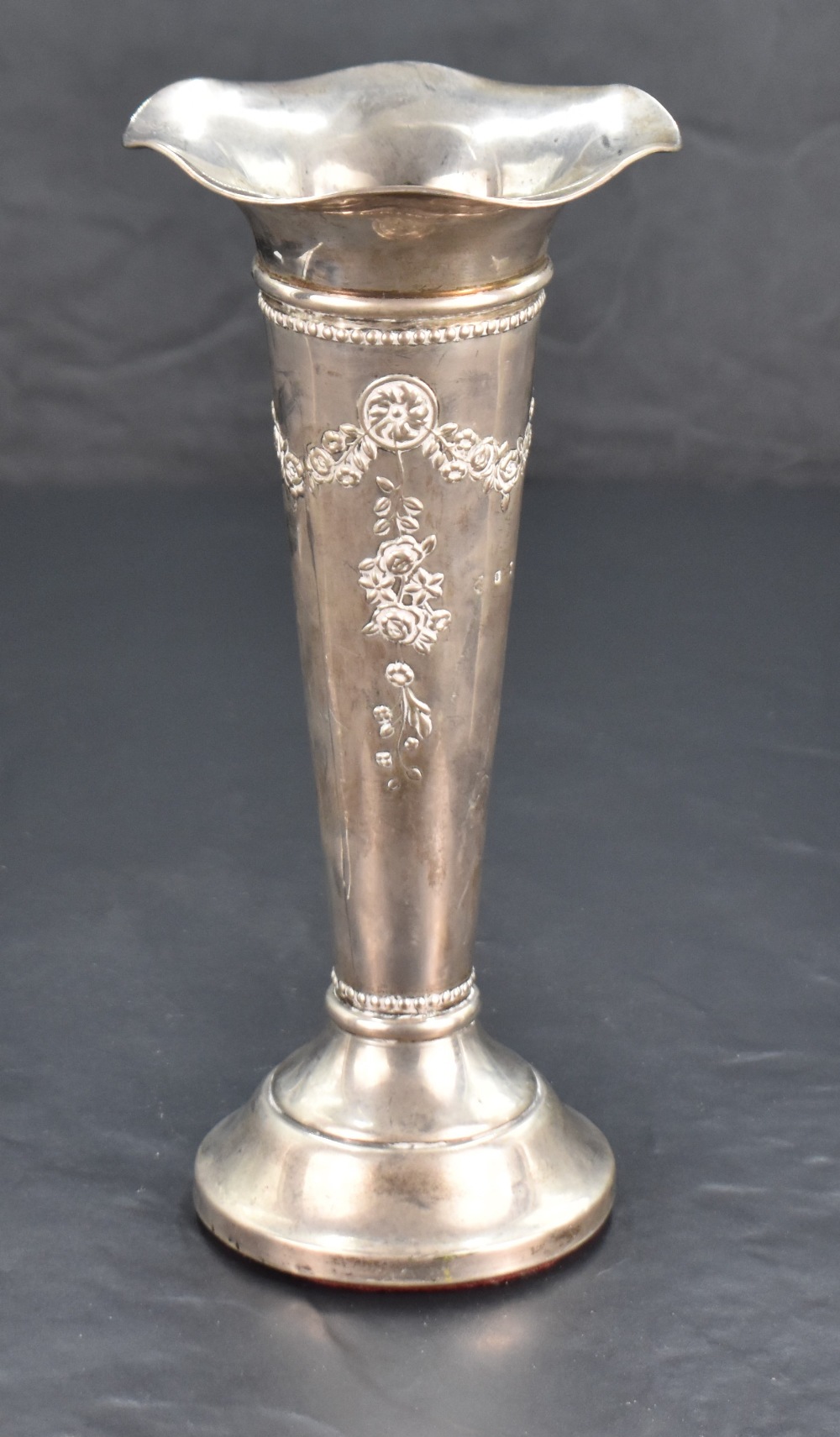 An Edwardian silver trumpet vase, with flared and ruffled rim over the tapering body embossed with