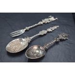 A pair of ornamental Dutch white metal spoons, with bowls embossed with landscape and figural scenes