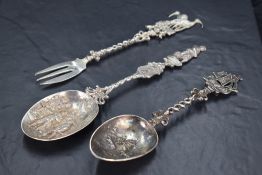 A pair of ornamental Dutch white metal spoons, with bowls embossed with landscape and figural scenes