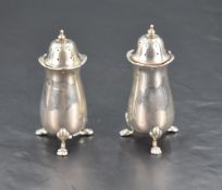 A pair of Edwardian silver pepperettes, each with pierced domed finial topped covers over plain