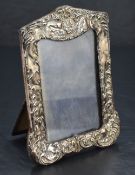 An Edwardian silver-mounted photograph frame, of shaped rectangular form embossed with foliate