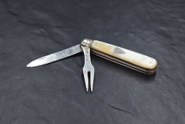 An Edwardian Mother-of-Pearl mounted, silver bladed and tined folding fruit knife and fork, of