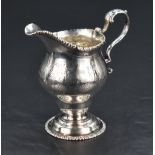 A George III white metal cream jug, of helmet form with gadrooned rim detail and bright-cut