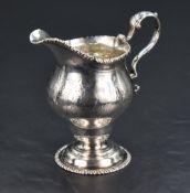 A George III white metal cream jug, of helmet form with gadrooned rim detail and bright-cut