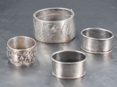 A Burmese white metal napkin ring, of compressed circular form decorated with a band of deities,