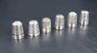 A group of six silver and white metal thimbles, of traditional design, two hallmarked silver, one