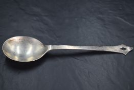 An Arts & Crafts silver spoon, the plain rounded bowl issuing a gently tapering stem finishing