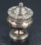 A 19th century silver pepperette, the stepped, domed and pierced finial-topped cover over a
