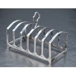 A George V silver six-division toast rack, of arched form with central carrying handle, marks for