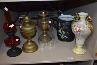 Three 19th/20th Century oil lamps, including a cranberry glass lamp, with chimneys, a Duchess Art
