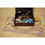 An oriental lacquered jewellery box containing assorted costume jewellery, including strings of