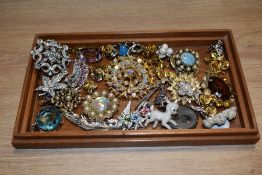 A small collection of costume jewellery brooches, including a yellow metal starburst style brooch,