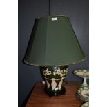 A glazed pottery table lamp, of Oriental design, on green ground, with shade, measuring 64cm tall