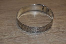 A silver belt style bangle having engraved decoration