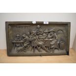 A resin moulded wall plaque, depicting a Dutch tavern scene, measuring 25cm x 50cm overall
