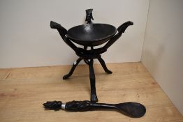 A primitive African hardwood bowl on folding tripod stand & spoon of matching design