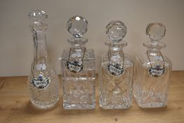 Four cut glass decanters, of graduating sizes, each having a Crown Staffordshire china spirit label,
