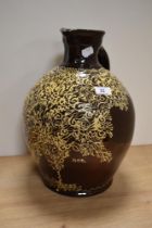 A Wetheriggs style slip glazed ewer or jug, on dark brown glazed grown, measuring 38cm tall