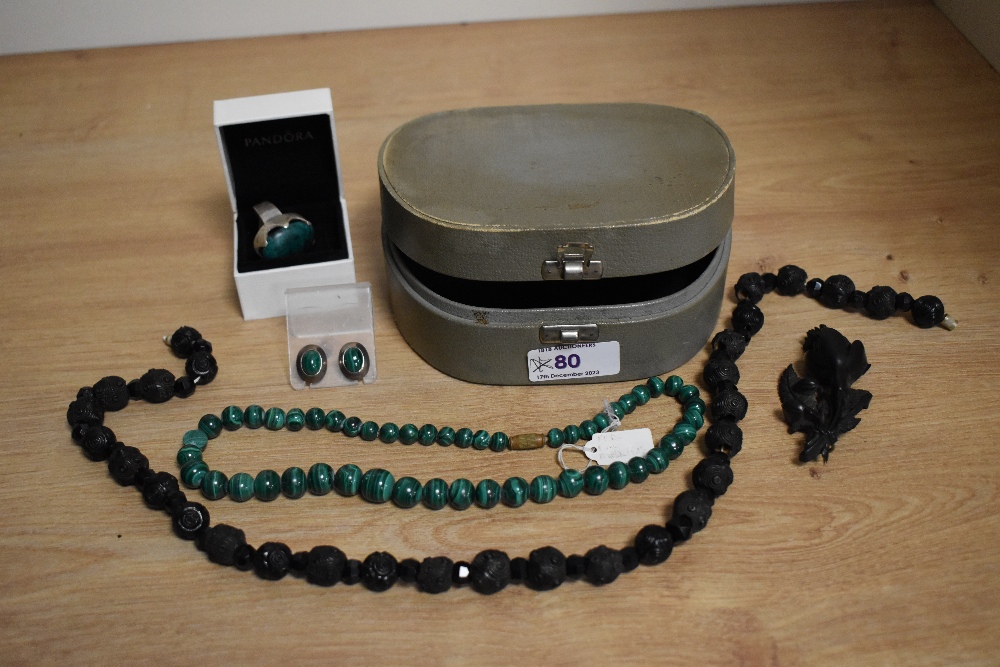 A vintage jewellery case containing a string of mourning beads, brooch, string of malachite beads