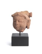 A PINKISH BUFF SANDSTONE HEAD OF A FEMALE DEITY, MADHYA PRADESH, CENTRAL INDIA, 11TH/12TH CENTURY