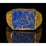 A LARGE FATIMID GOLD GRANULATED RING WITH A RECTANGULAR BEZEL TABLE SET WITH A LAPIS LAZULI.