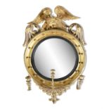 A 19TH CENTURY CONVEX MIRROR, with carved eagle cresting, the glass plate within a reeded ebon