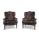 A PAIR OF GEORGIAN STYLE BUTTON BACK WINGED ARMCHAIRS, 20TH CENTURY, covered in a claret hide