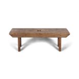 A STAINED PINE LOW STOOL, the seat pierced with central spade on plain slated side supports.