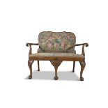 A GEORGE II STYLE WALNUT LOVE SEAT upholstered in needlework tapestry, with stylised eagle head