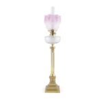 A VICTORIAN GLASS AND BRASS MOUNTED OIL LAMP with clear glass reservoir, raised on Corinthian