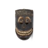 A PACIFIC ISLANDS FACE MASK with stylised features, broad grin, ochre eyes. 29cm long