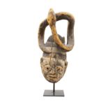 A LARGE AFRICAN YORUBA GELEDE MASK with white pigment, surmounted with a coiled serpent,