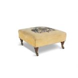 AN UPHOSTERED ARMORIAL LOW STOOL, the yellow fabric seat embroidered with an elaborate coat of