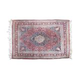 A LARGE PERSIAN RED GROUND WOOL CARPET the open centre field woven with a large cartouche