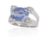 A SAPPHIRE AND DIAMOND RING, of sculptural design, the oval-shaped sapphire weighing 8.