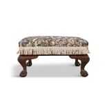 AN UPHOLSTERED MAHOGANY FRAMED STOOL, c. 1930, of rectangular shape, covered in a floral