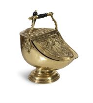 A VICTORIAN EMBOSSED BRASS HELMET-SHAPED COAL SCUTTLE, with raised handle, incorporated shovel